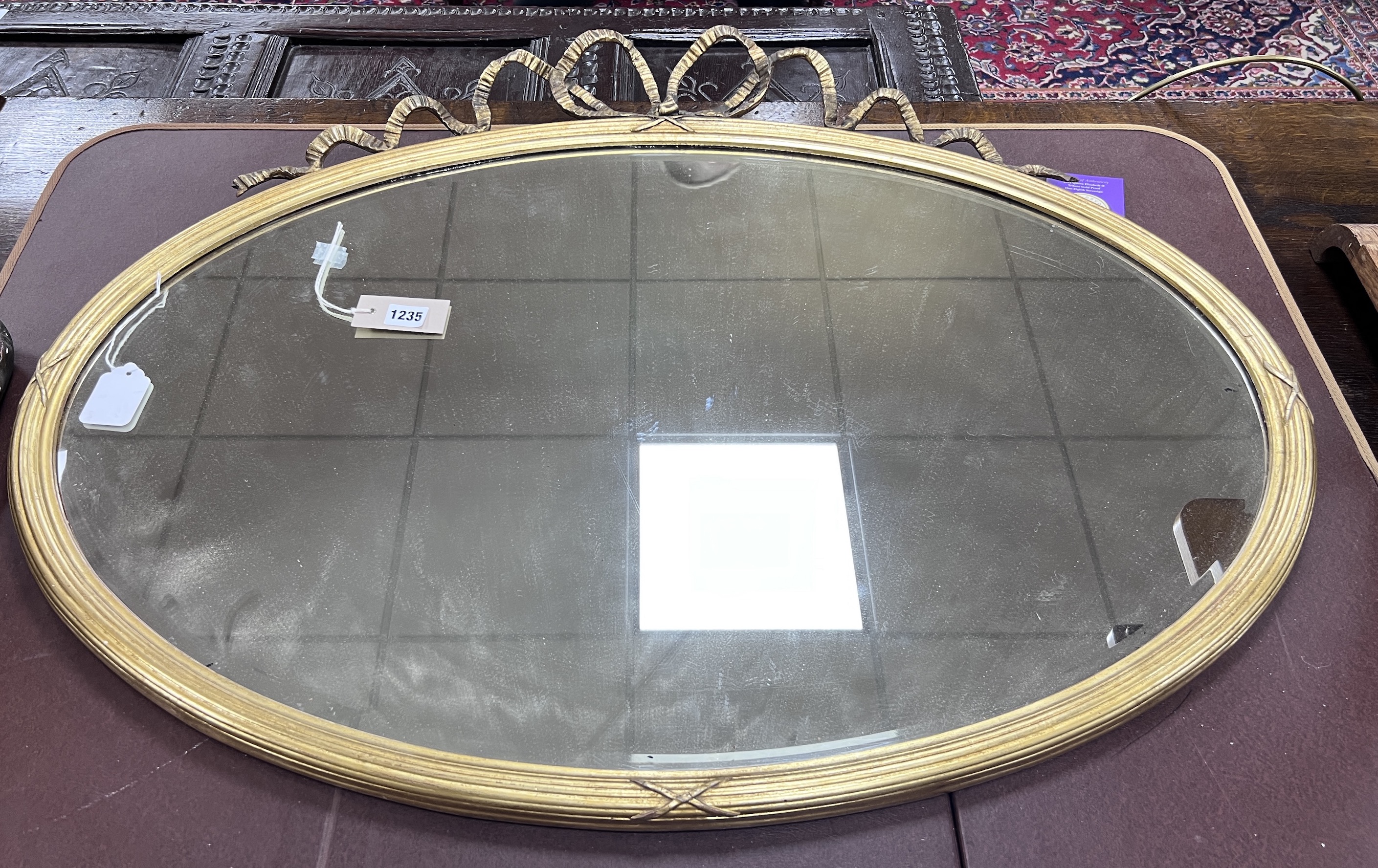 An Edwardian oval giltwood and gesso wall mirror with ribbon crest, width 93cm, height 71cm